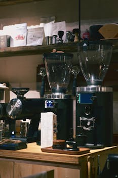 Espresso machines and coffee grinders on a wooden counter in a cozy coffee shop.