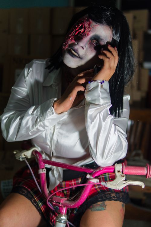 Free A spooky portrayal of a zombie-themed costume with horror makeup and a bicycle prop, perfect for Halloween themes. Stock Photo