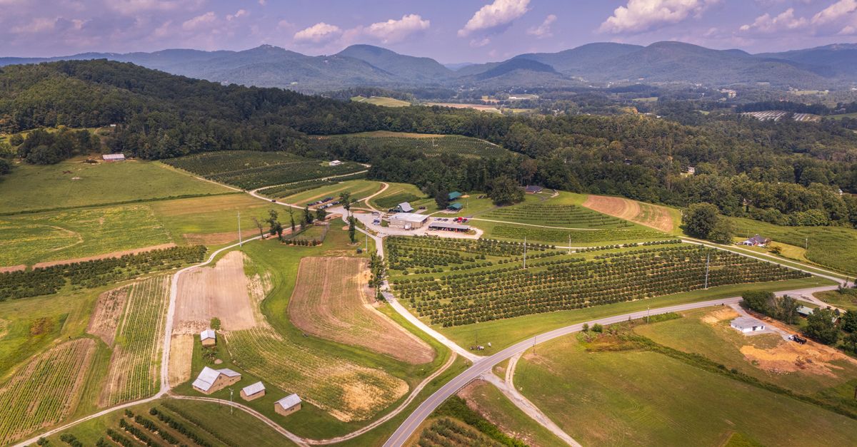 Aerial shot of farmland surrounded by mountains in North Carolina's Blue Ridge region.