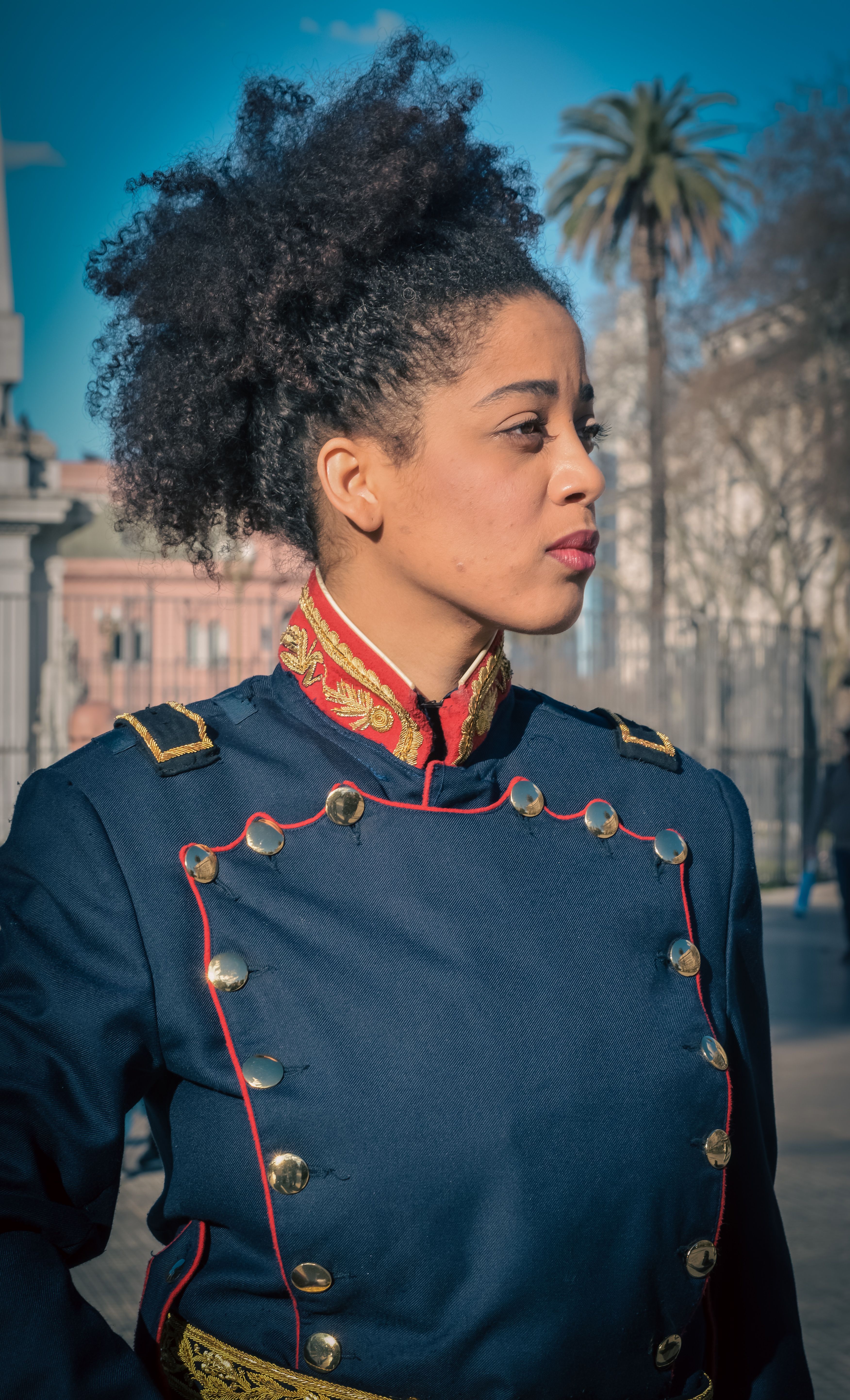 A woman in a historical military uniform, in Buenos Aires, Argentina, under a clear blue sky.