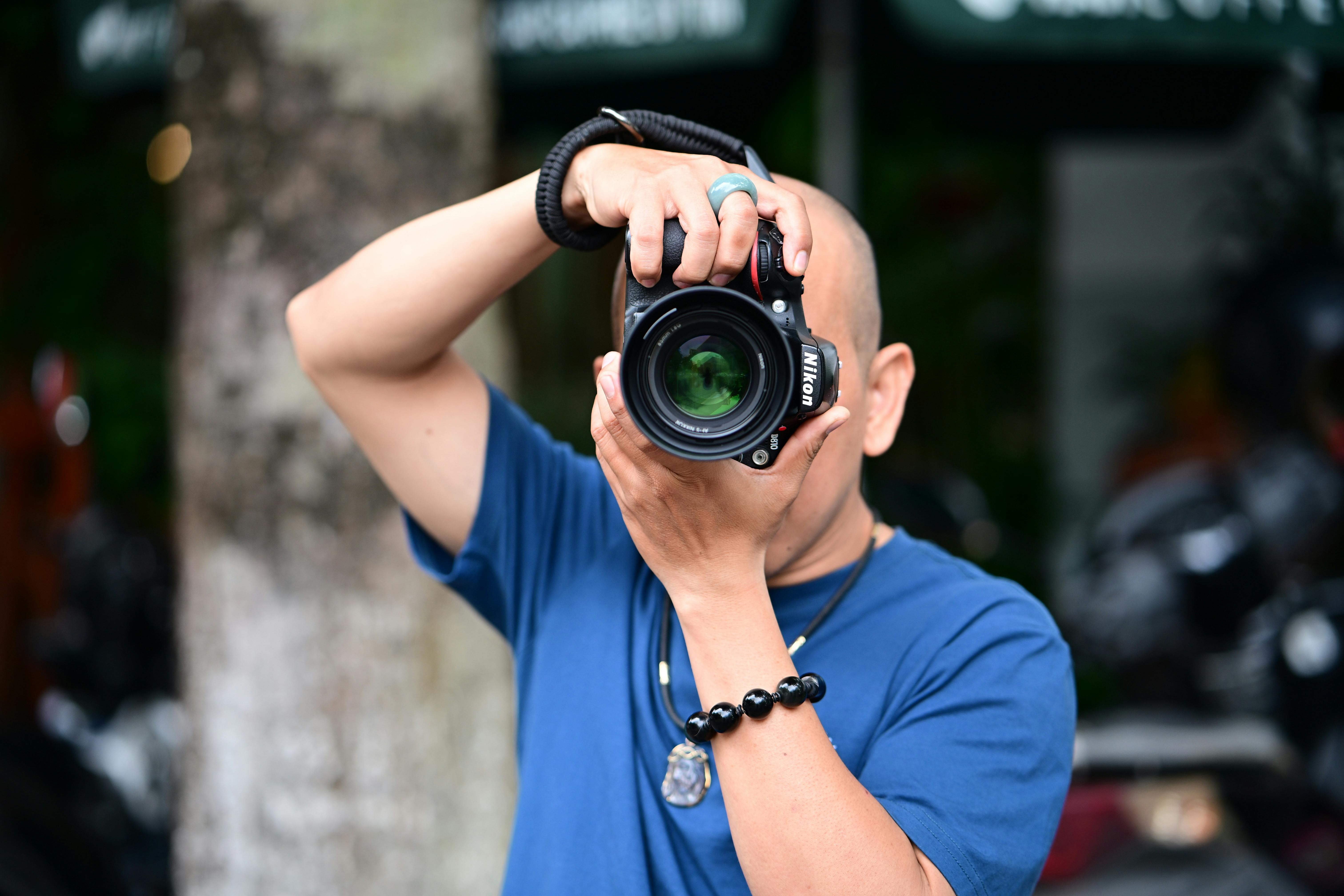 A person using a DSLR camera outdoors, focusing on capturing the perfect shot.