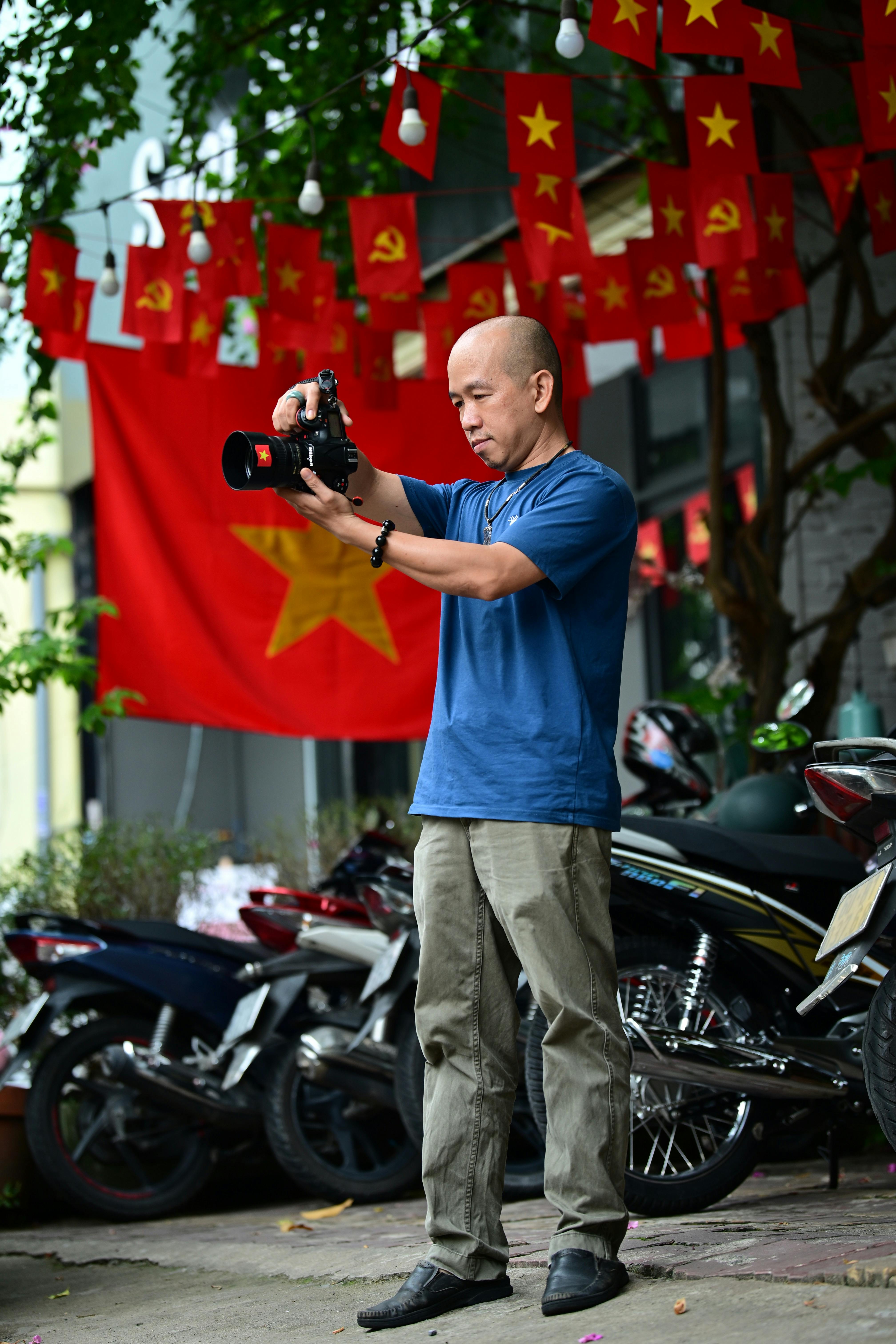 Photographer in blue shirt capturing street scene with motorbikes.