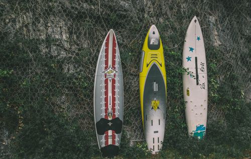 Free Three colorful surfboards against a rocky wall create a dynamic outdoor scene. Stock Photo