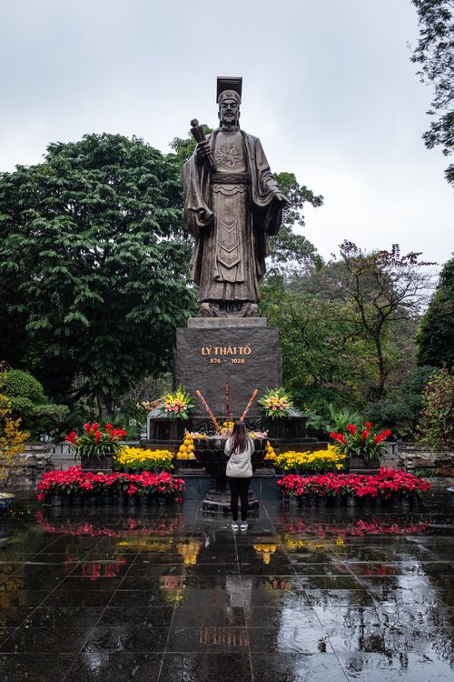 Free A person stands before the statue of Lý Thái Tổ in Hanoi, surrounded by colorful flowers. Stock Photo