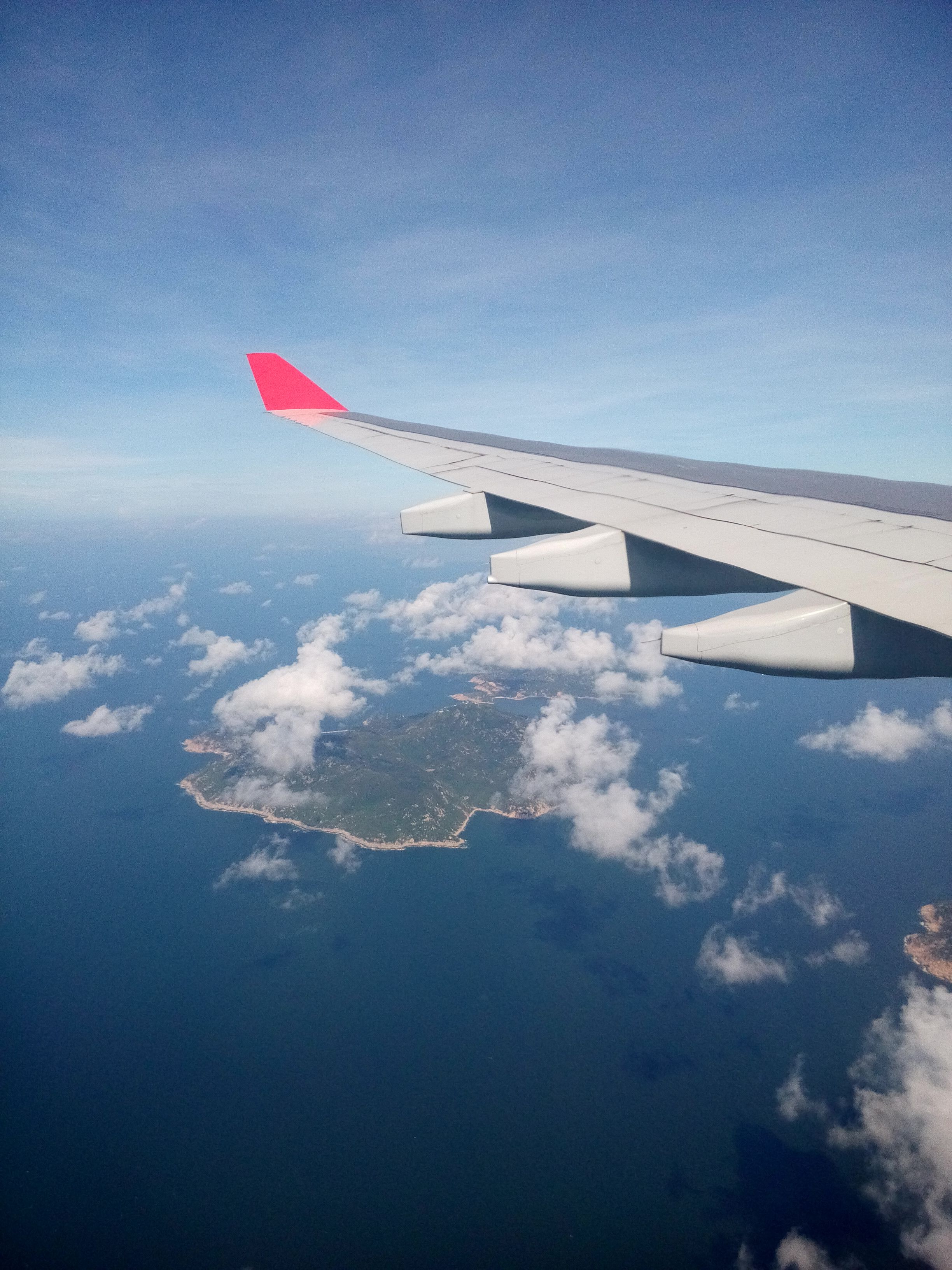 Scenic view of an island from an airplane window with blue sky.