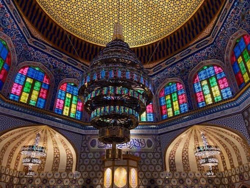 Free Intricate mosque interior featuring colorful stained glass windows and ornate chandeliers. Stock Photo