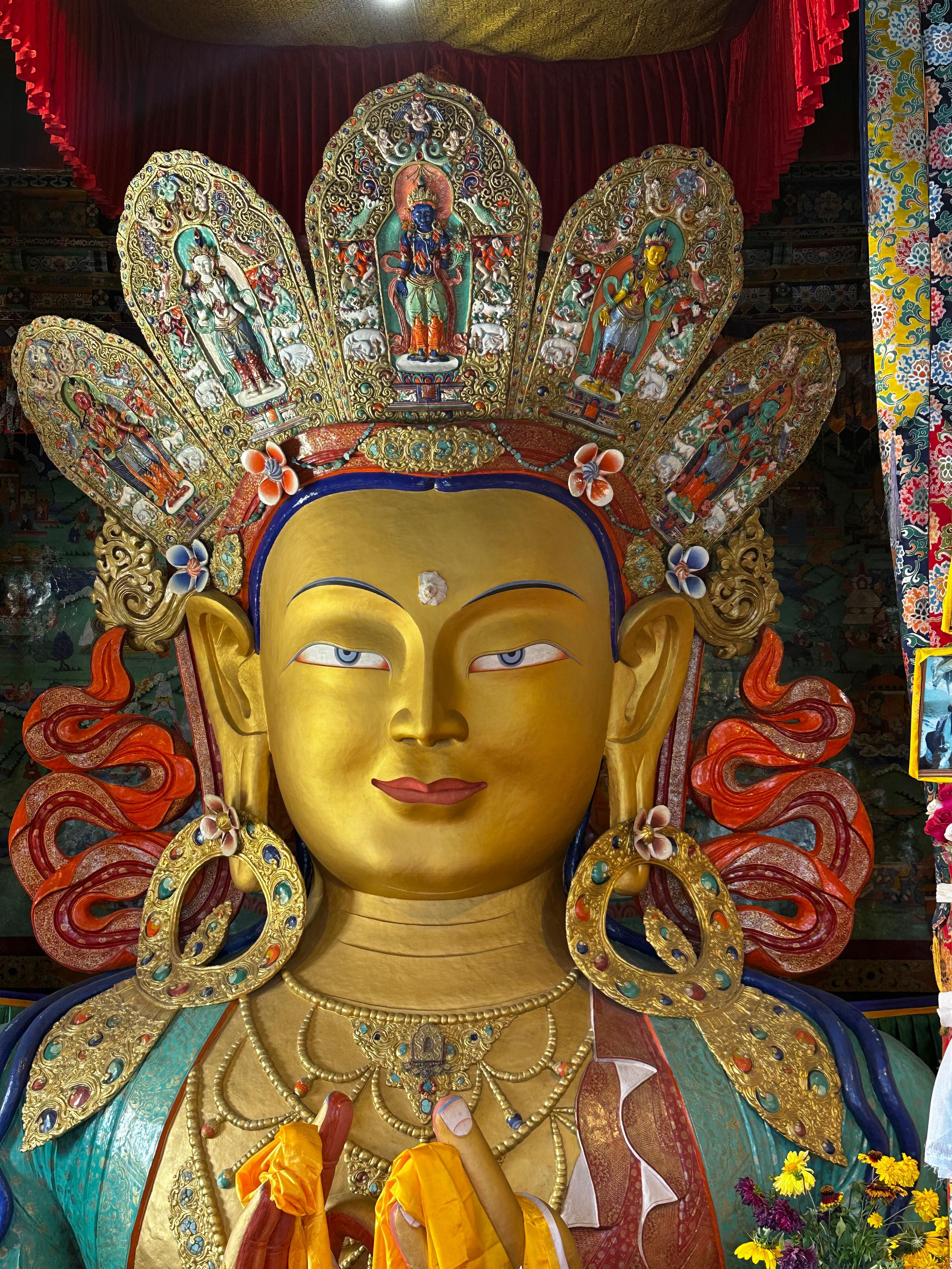 Vibrant Buddha statue adorned with colorful decorations in a Leh monastery.