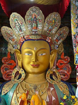 Vibrant Buddha statue adorned with colorful decorations in a Leh monastery.