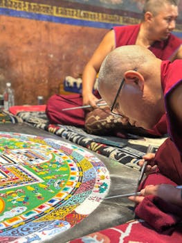 Monks meticulously creating a traditional sand mandala in a vibrant temple setting in Leh.