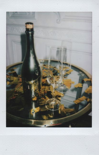 Champagne bottle with glasses and gold confetti on a table, perfect for festive celebrations.