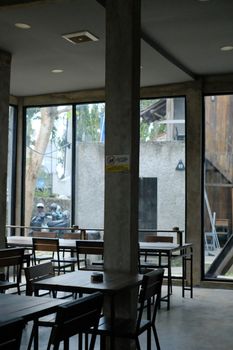 Spacious cafe area with tall windows and minimalistic furniture, perfect for a quiet break.
