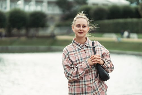 Elegantní žena u jezera v kostkované košili