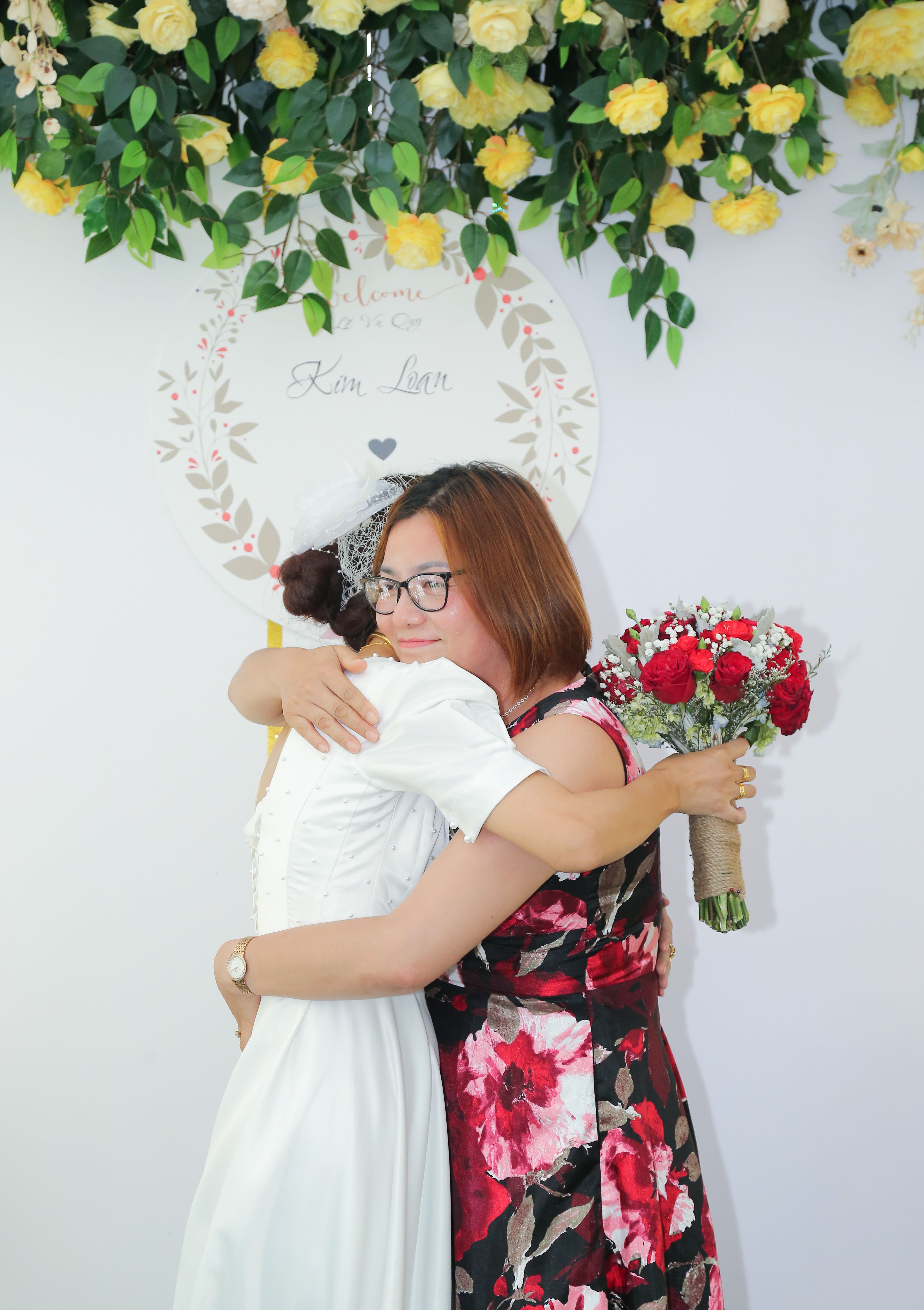 A touching moment between friends at a wedding, surrounded by beautiful floral decor.