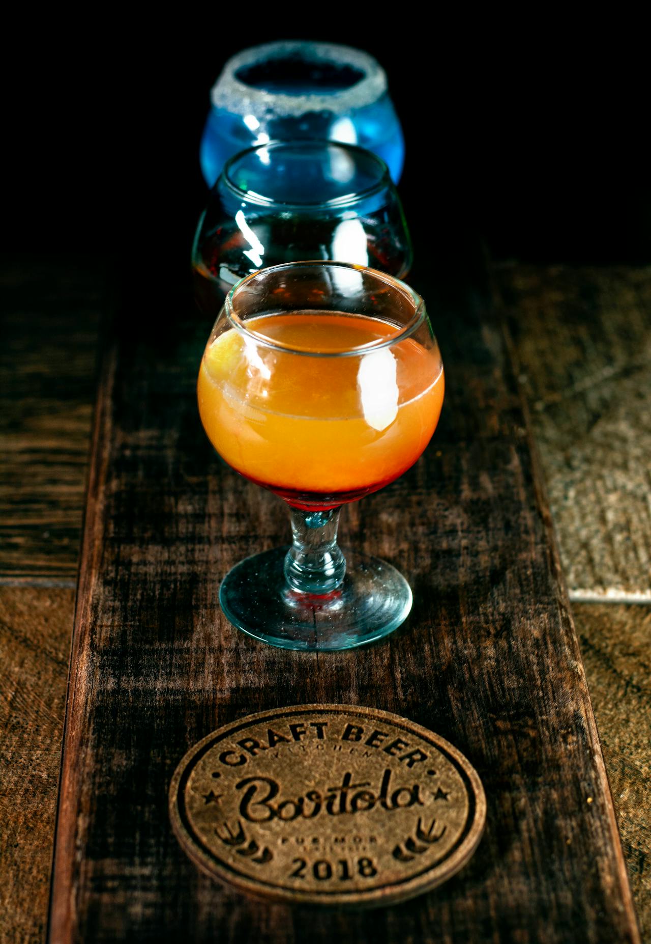 Vassoio di legno con bicchierini di cocktail artigianali colorati assortiti