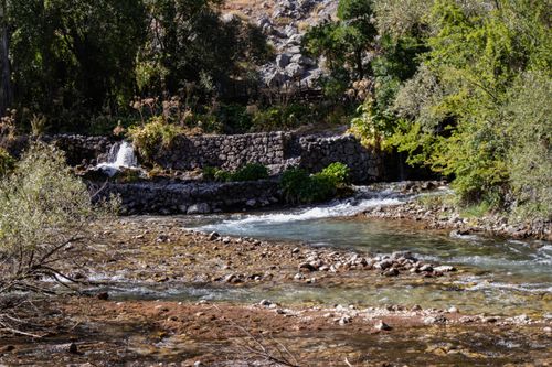 Free Serene river stream with stone wall in Tunceli, Türkiye, surrounded by lush greenery. Stock Photo