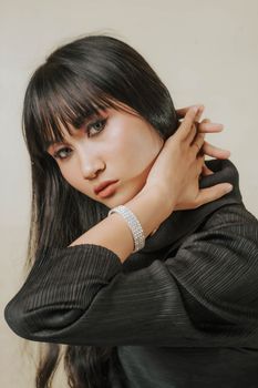 Elegant portrait of a young woman in black with striking jewelry and makeup.