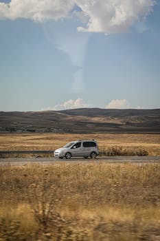 A car travels on a road through the scenic landscape of Van, Turkey.