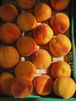 Top view of fresh juicy peaches in a crate, perfect for summer recipes.