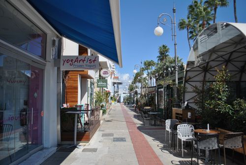 Free A picturesque street with cafes and palm trees under a bright blue sky. Stock Photo
