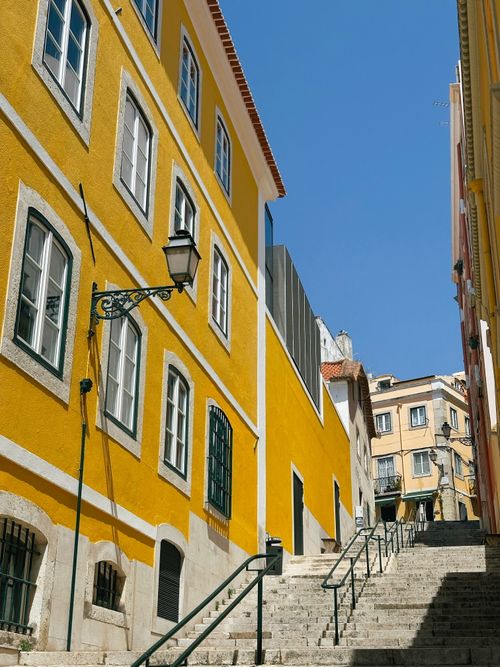 Free Bright sunny day highlights vibrant yellow buildings and quaint street in Lisbon, Portugal. Stock Photo