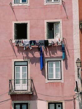 Vibrant clothes drying on a pink building facade under clear daylight.