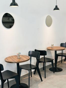 Contemporary cafe interior featuring wooden tables, black chairs, and minimalist decor.