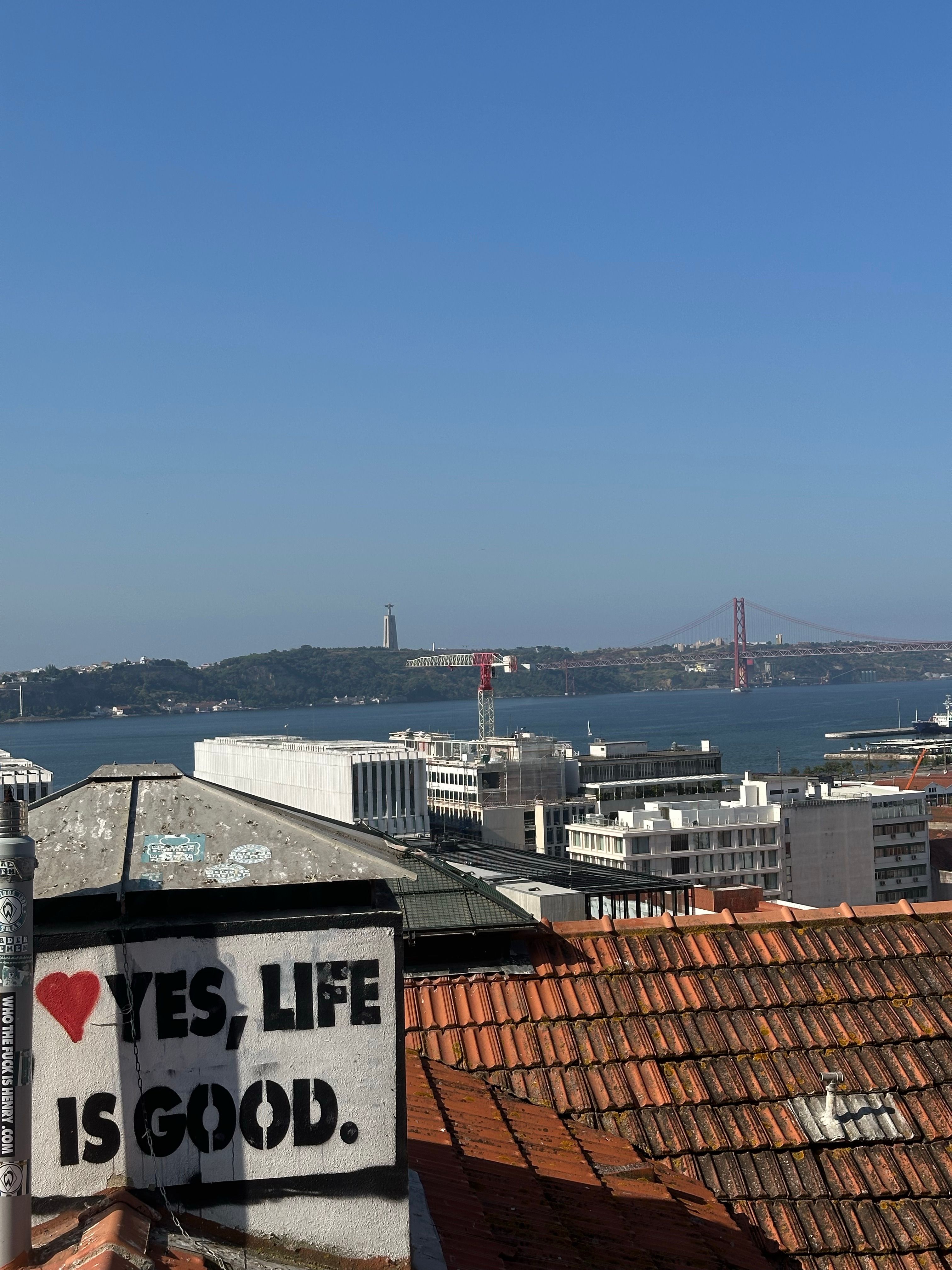 Rooftop view of Lisbon featuring the iconic 25 de Abril Bridge and vibrant graffiti.