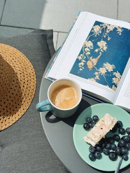 A cozy outdoor setup with coffee, berries, and a book, perfect for relaxing days.