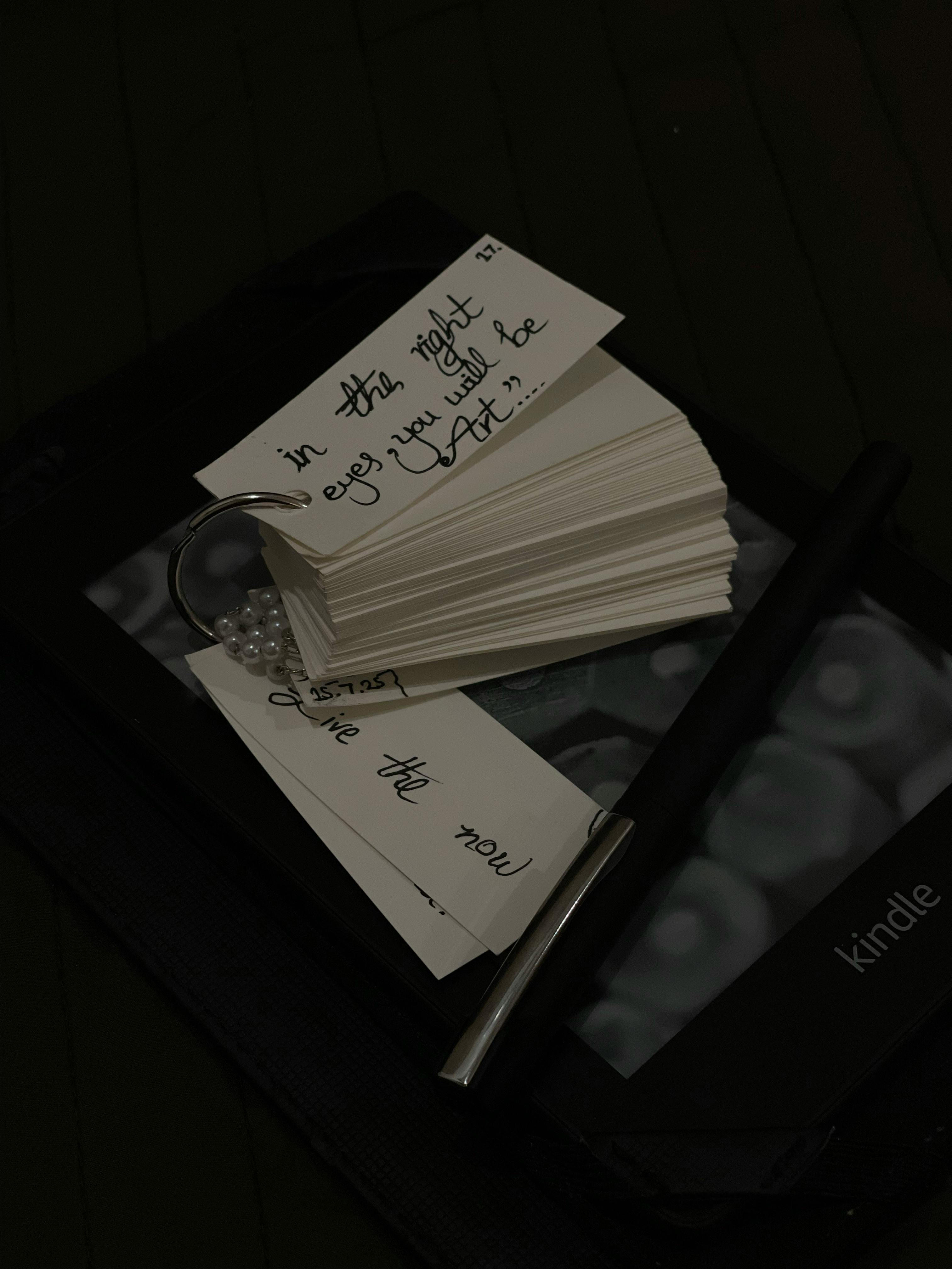 bezplatná Hromada kartiček s inspirativními citáty, pero a Kindle pro inspiraci ke čtení. Základová fotografie