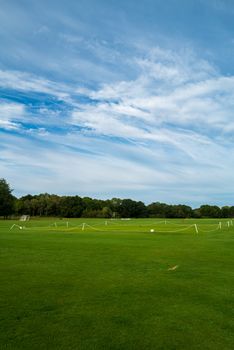 Wide open sports field with lush grass and clear sky, ideal for outdoor events and sports.