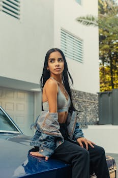 在现代城市环境中，一位穿着休闲装的年轻女子在汽车旁摆姿势