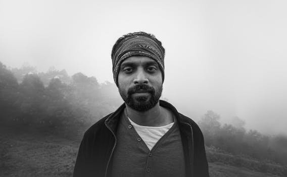 雾气弥漫的户外，一名留着胡须、戴着头巾的男子黑白肖像