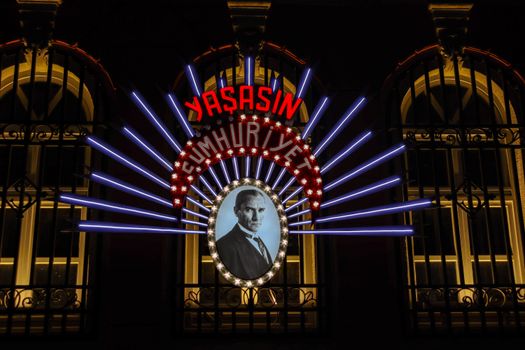 Neon sign with portrait under 'Yaşasın Cumhuriyet', night view.