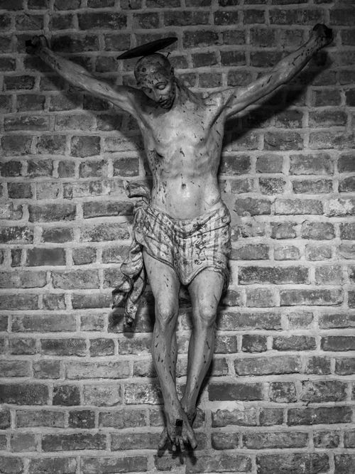 Free A profound black and white image of a crucifix sculpture on a brick wall. Stock Photo