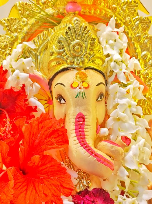 Free Captivating Ganesh idol adorned with vibrant flowers, symbolizing spirituality and festivity. Stock Photo
