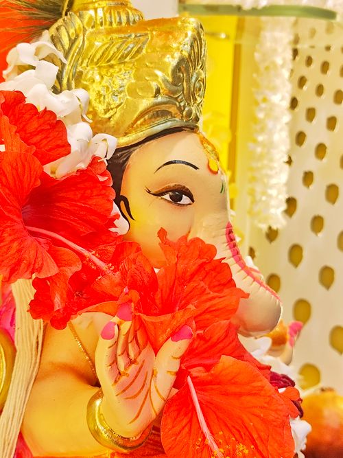Free A colorful Ganesh idol adorned with vivid red hibiscus flowers, perfect for Ganesh Chaturthi celebrations. Stock Photo