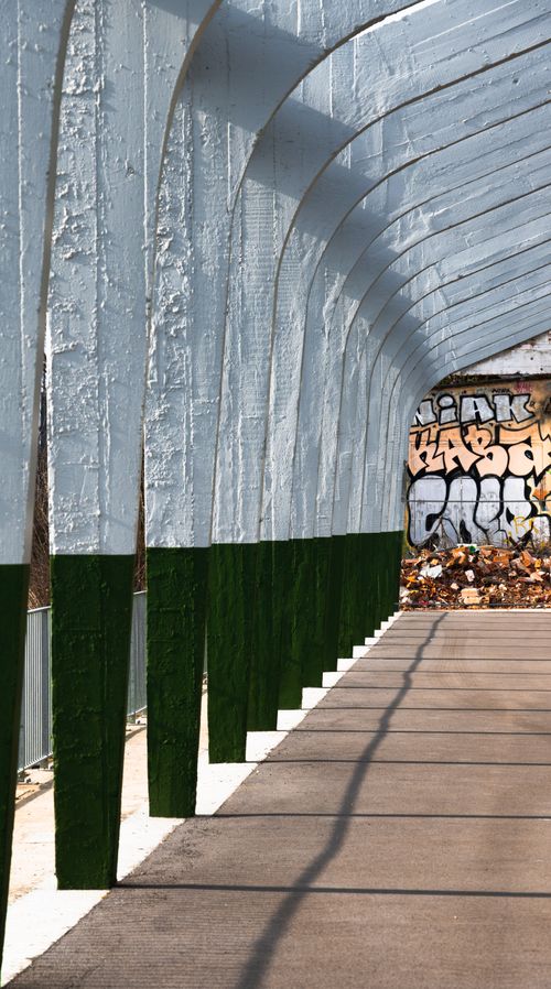 Free Arched concrete structure with graffiti in Toulouse, France. Urban street art meets modern architecture. Stock Photo