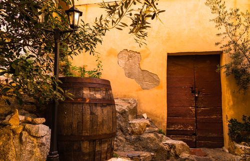 Free A charming rustic scene with an old door, wine barrel, and stone pathway in Corsica, France. Stock Photo
