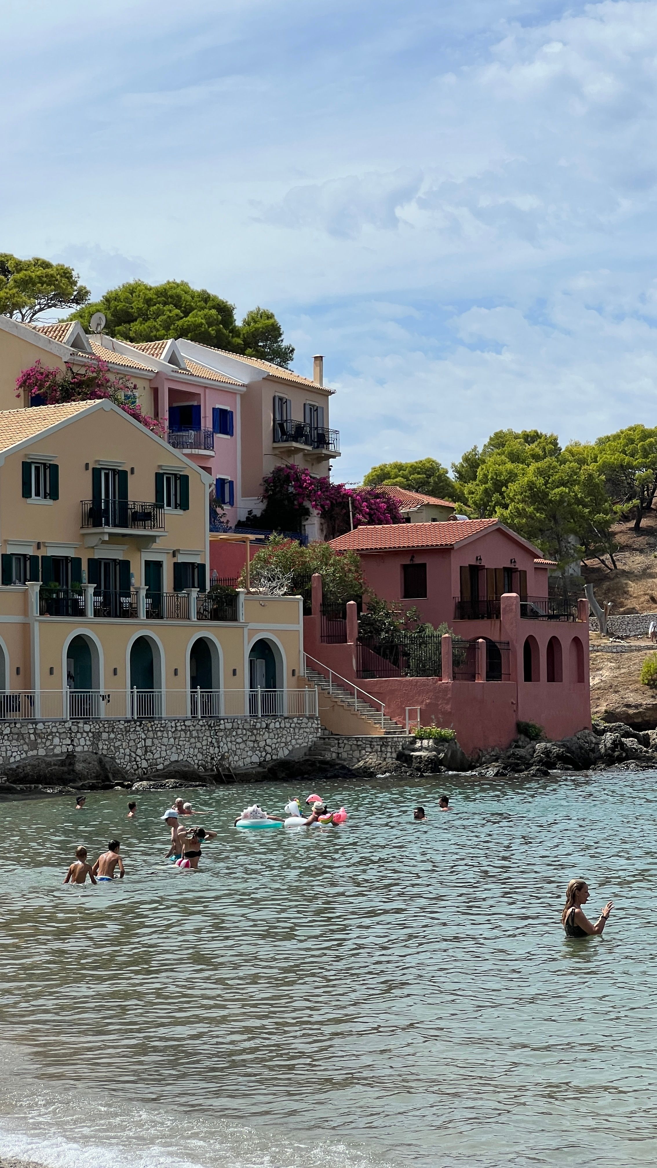 Charming seaside village with colorful houses by the beach, people enjoying summer waters.