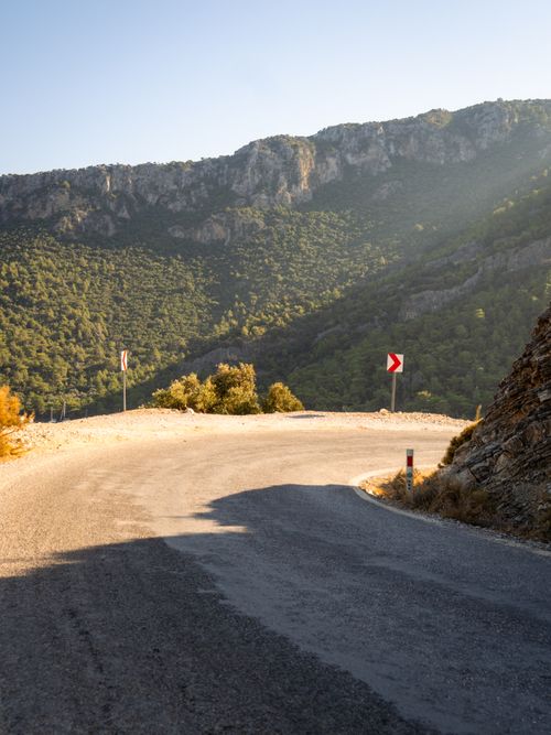 Free Curved mountain road with scenic views under soft sunlight, perfect for travel and adventure themes. Stock Photo