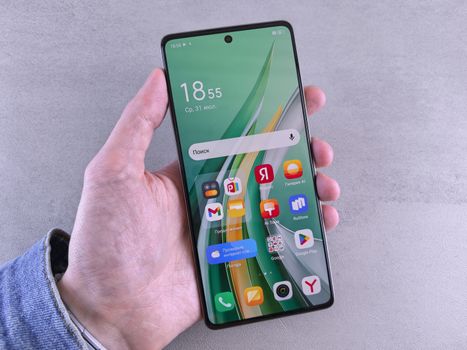 Close-up of a hand holding a smartphone with a vibrant app-filled screen against a neutral background.