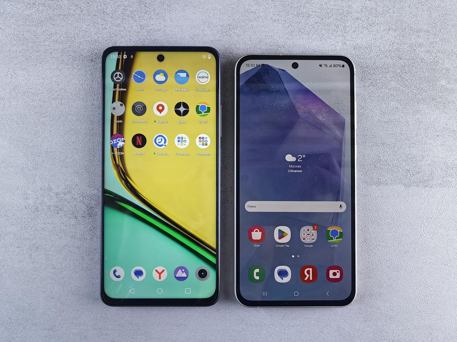 Top-down view of two modern smartphones with home screens displayed on a textured surface.