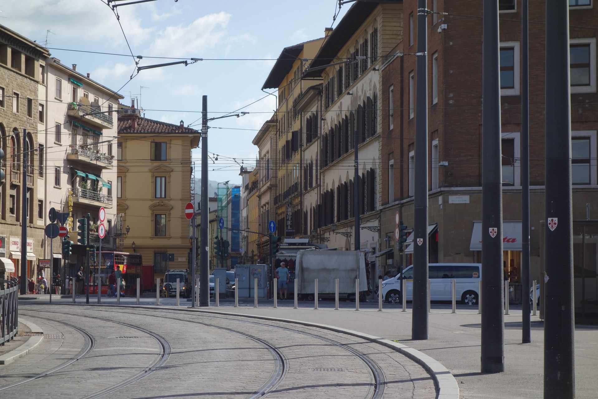 A sunny street view of Florence's characteristic urban architecture with tram tracks in Italy.