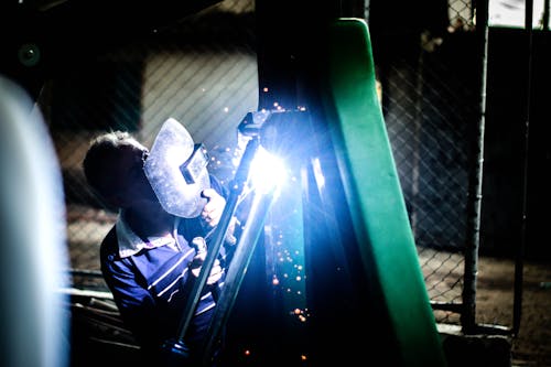 Industry worker welding iron pieces at night