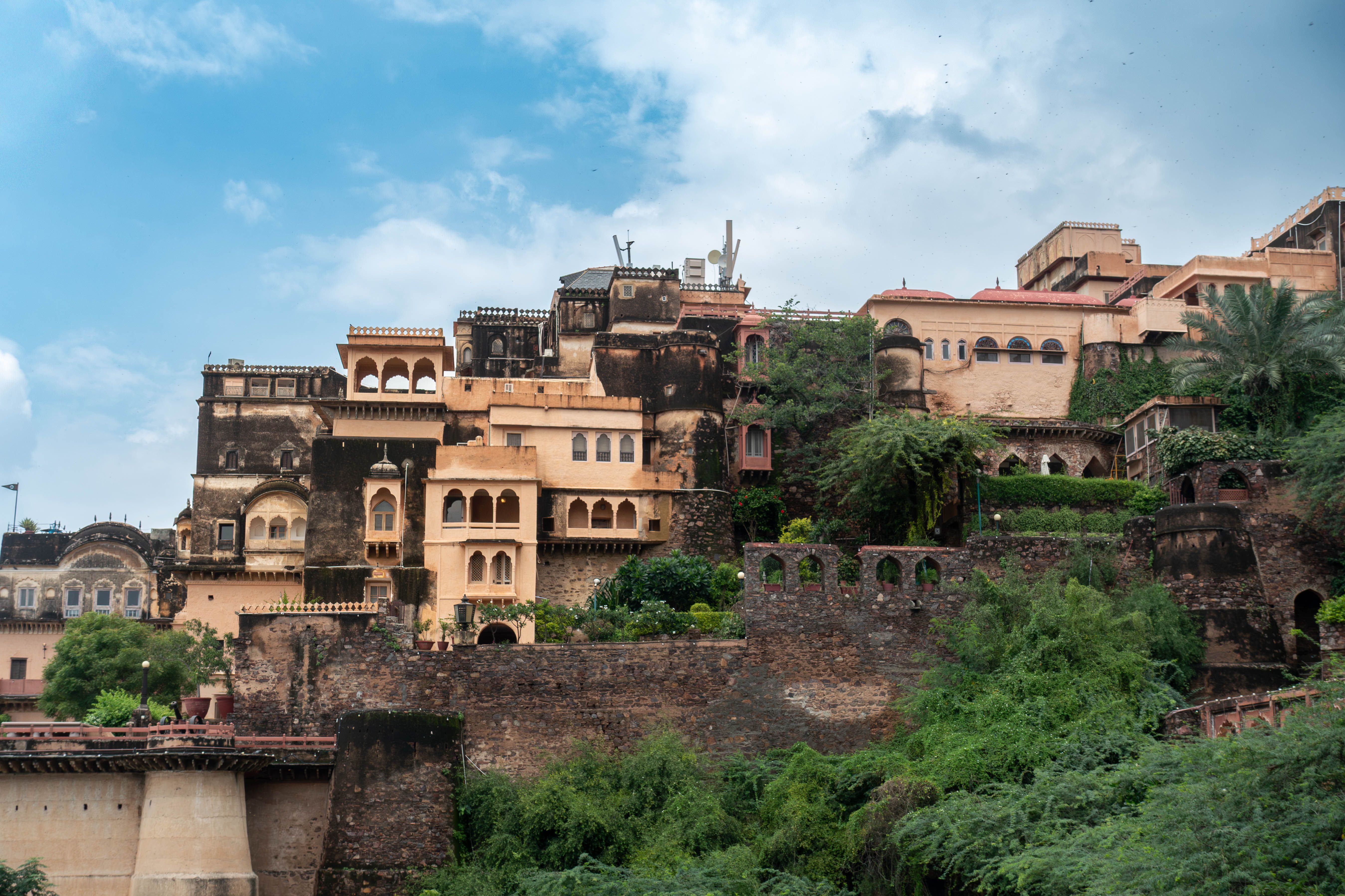 Captivating view of Neemrana Fort-Palace amidst lush greenery under a bright blue sky.