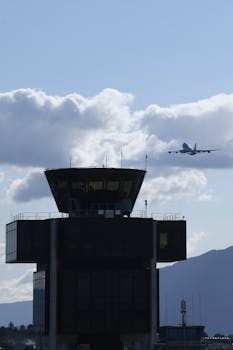 An airplane takes off into a blue sky near the control tower at Geneva Airport in Switzerland.
