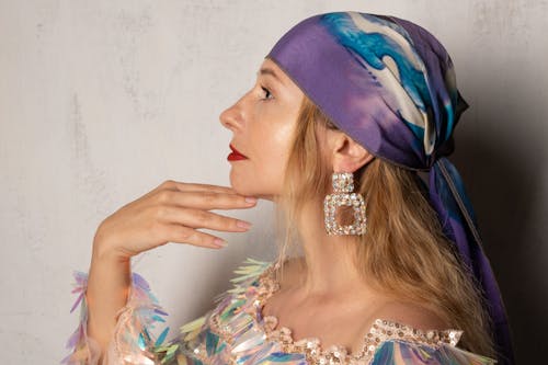 Profile of a woman wearing a colorful headscarf, large earrings, and a vibrant outfit, exuding elegance and style.