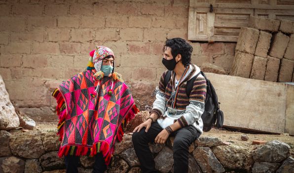 Two men in traditional Andean attire and masks converse in Cusco, Peru.