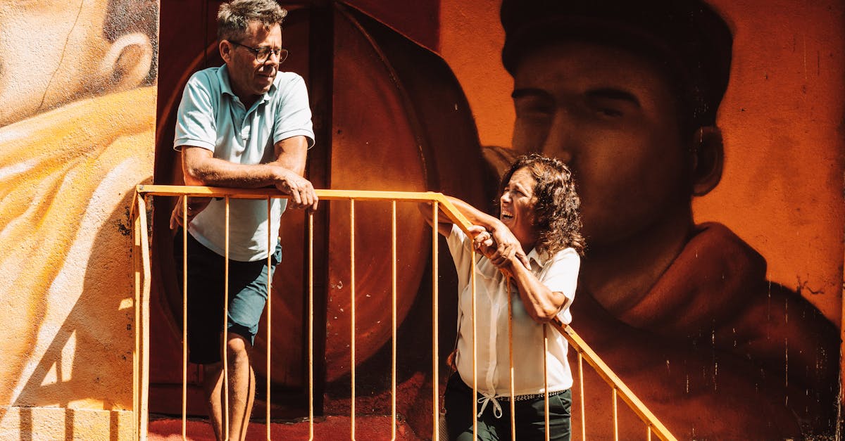 Two people engage on stairs in front of a vibrant mural in Macedo de Cavaleiros, Portugal.