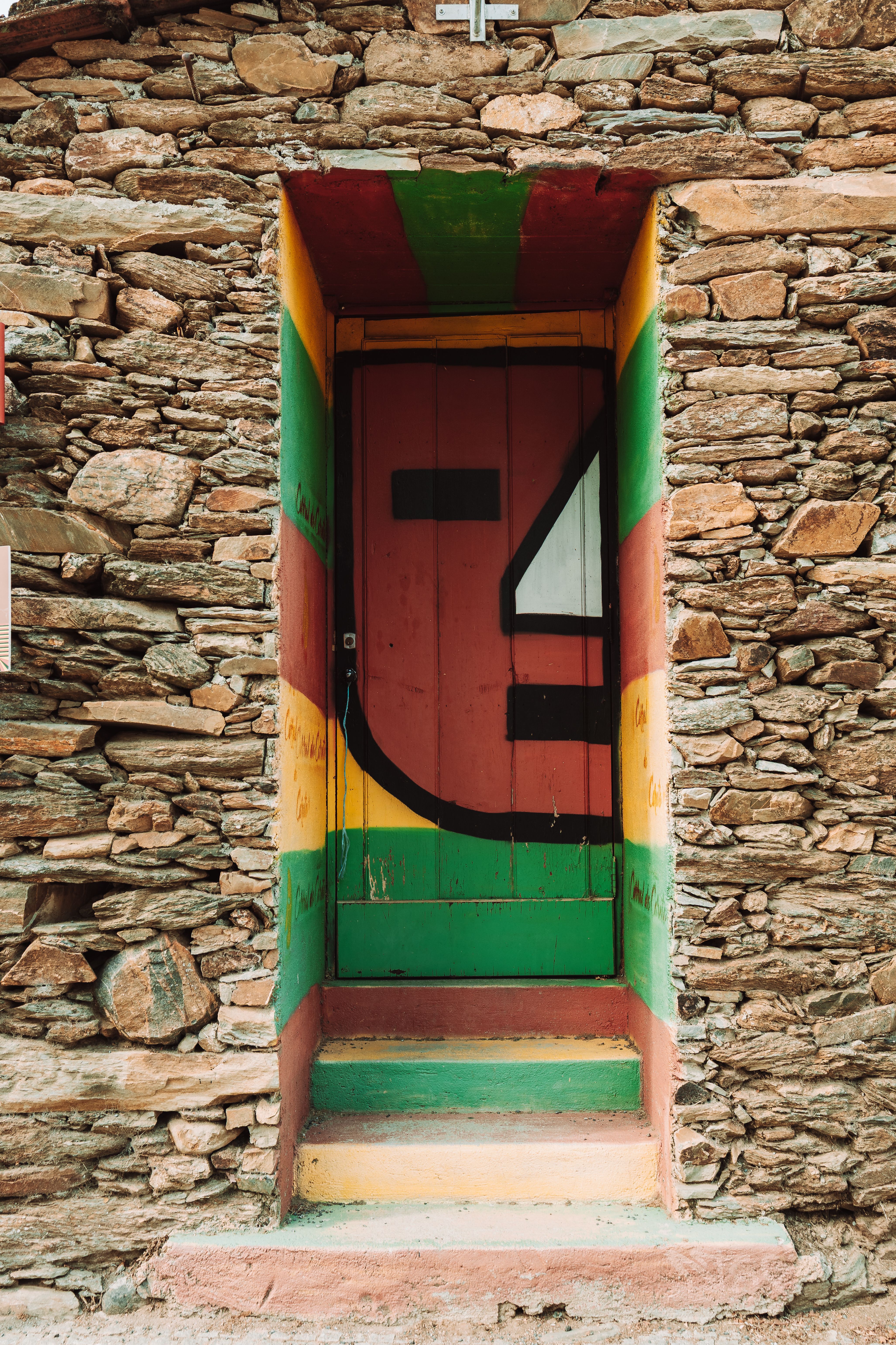 A vibrant painted door set in a stone wall in Macedo de Cavaleiros, Portugal.